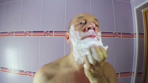 The man in the bathroom puts shaving foam on his face — Stock Video