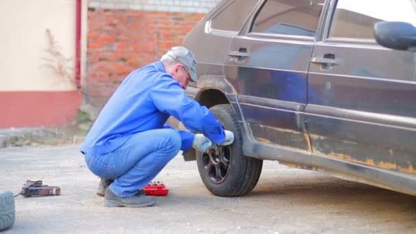 Mannelijke automonteur met een moersleutel beveiligt een auto wiel — Stockvideo