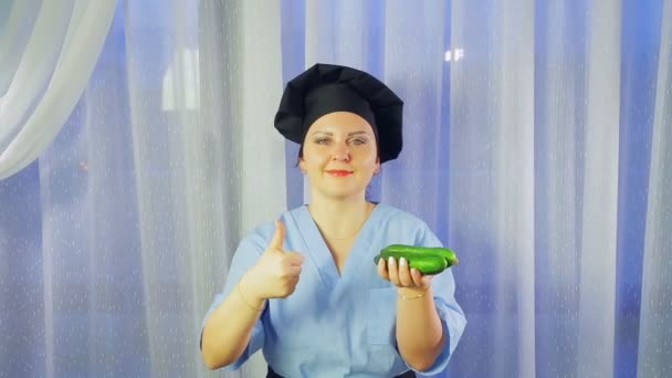 Žena vaří v zástěře se usmívá, drží okurky v ruce a ukazuje třídu. — Stock video
