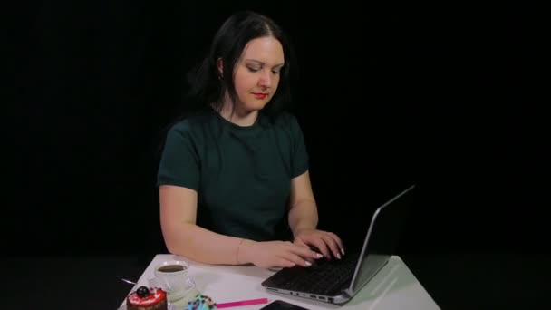 Una chica morena en un café trabaja con una computadora y bebe café en un café — Vídeos de Stock