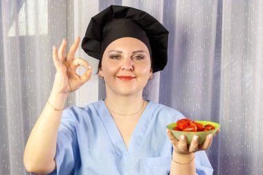 Pozitif kadın aşçı elinde taze kiraz domates tutarak.