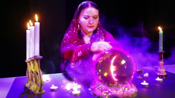 A gypsy woman in a magic salon in puffs of smoke guesses on a crystal ball and a euro sign appears in it. — Stock Video