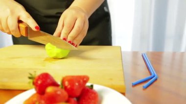 Kadın olgun kiviyi tahta bir bıçakla kesiyor.