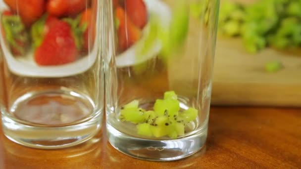 Женщина кладет кусок зеленого киви в бокал для коктейлей — стоковое видео