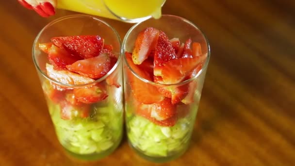 A woman pours fresh strawberry and kiwi juice in a glass — Stock Video
