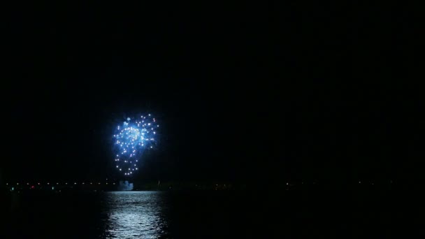 A colorful scattering of festive fireworks in the night sky above the river is reflected in the water. Time laps. — Stock Video