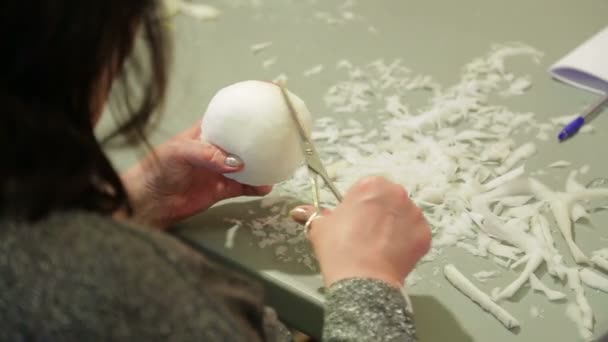 The girl cuts with scissors foam rubber for a toy giving it a round shape. — Stock videók