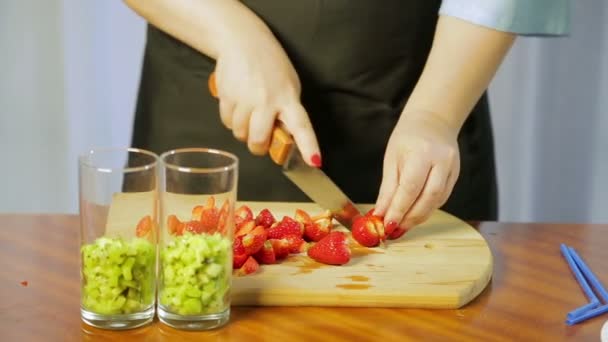 En kvinna klipper mogna jordgubbar med en stor kniv på en trä kartong med en stor kniv — Stockvideo