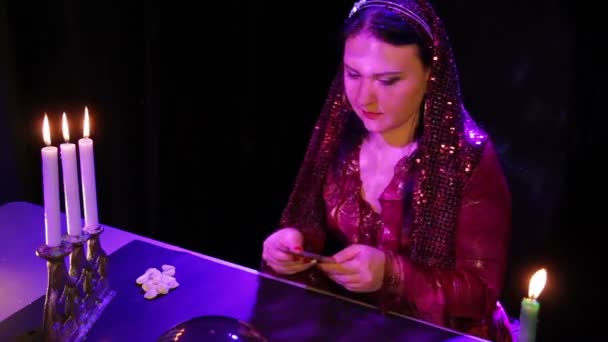 Een jonge zigeuner met kaarsen in de reflecties leidt de kaarten boven de spiegel bal — Stockvideo