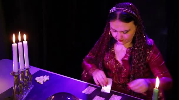 Une femme gitane dans une robe rouge avec des chandeliers lit l'avenir dans les cartes — Video