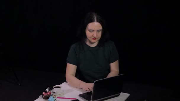 Une femme à une table dans un café tapant sur un clavier avec un ordinateur et buvant du café . — Video