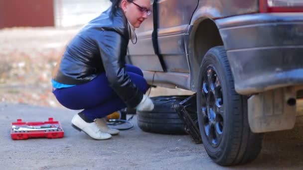 En kvinna med en knekt sänker bak sidan av bilen till marken — Stockvideo