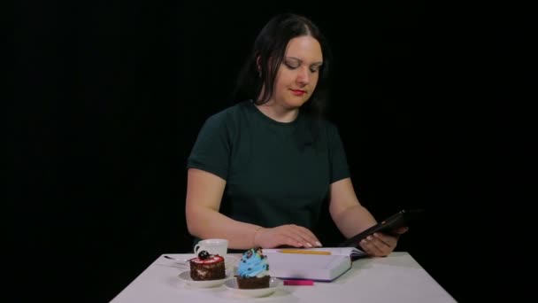 Bir kafede bir esmer kız bir tablet ile çalışır ve bir kafede kahve içecekler — Stok video