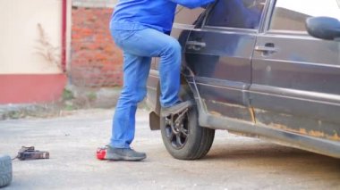 Bir anahtar ile erkek oto tamircisi bir araba tekerleği güvenli