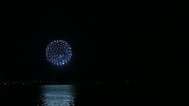 Het vuur verstrooiing van vuurwerk in de nachtelijke hemel boven de rivier wordt weerspiegeld in het water. Tijd ronden. — Stockvideo