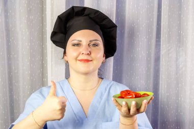 Pozitif kadın aşçı elinde taze kiraz domates tutarak.