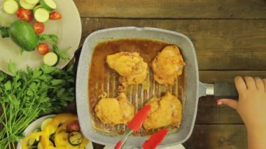 Bir ızgara tavada maşa tavuk ile karıştırma kadın el. Zaman turunda. Yukarıdan görüntüle