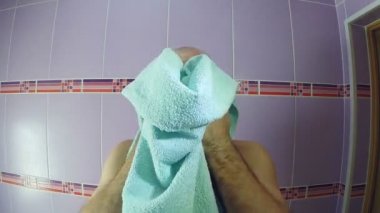 Banyoda bir adam tıraş sonrası havluyla yüzünü siliyor.