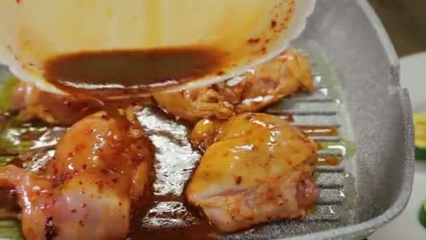 Una mano de mujer pone el pollo en la sartén y vierte la salsa sobre ella. — Vídeos de Stock
