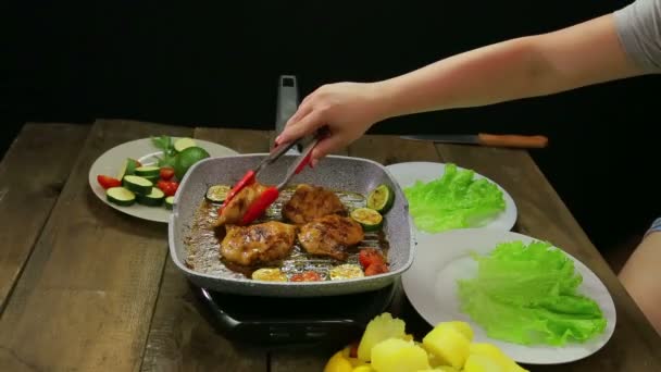 La mano femenina pone trozos de pollo en un plato con ensalada verde — Vídeo de stock