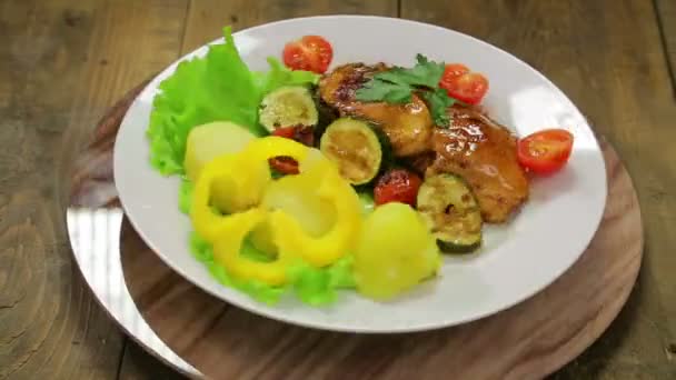 Un plato giratorio con un plato de pollo a la parrilla y un guarnición de verduras — Vídeo de stock