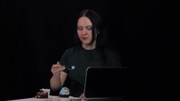 Una donna a un tavolo in un caffè beve caffè e mangia una torta dolce — Video Stock