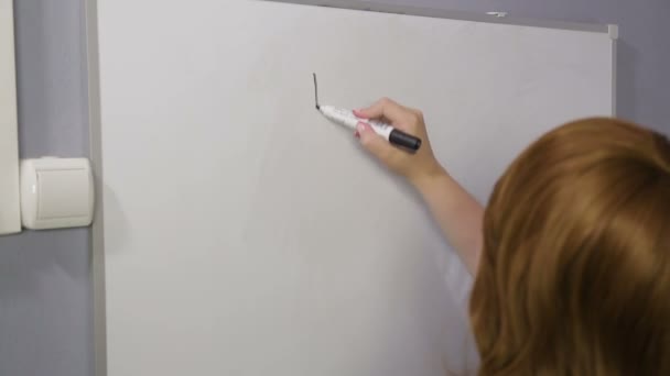Bir kadın sırtıile duruyor ve beyaz bir tahta üzerinde para işaretleri çizer — Stok video