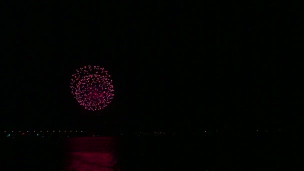 Chispas de fuego multicolores fuegos artificiales festivos en el cielo nocturno sobre el río reflejándose en el agua — Vídeos de Stock