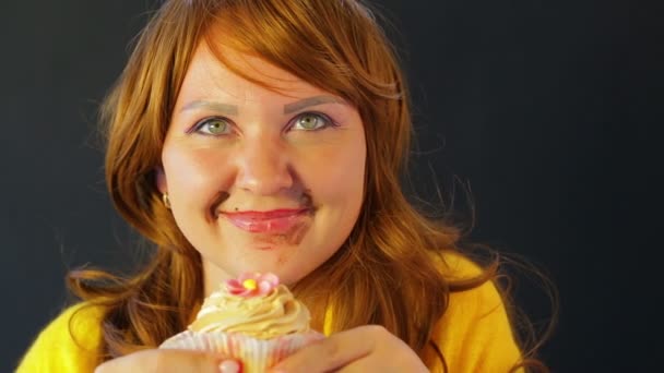 A red-haired young woman with a chocolate-stained face after a diet eats cakes while no one sees — Stock Video