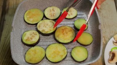 Maşa ile bir kadın el ızgara patlıcan kavurma döner