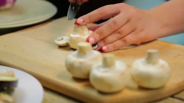 Bir kadın ahşap tahta üzerinde bir bıçak ile dilimleri içine champignon mantar pirzola.