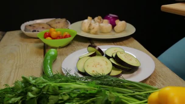Eine Frau legt Auberginen in Scheiben geschnitten in einen weißen Teller — Stockvideo