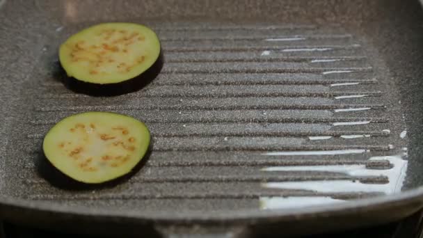 Female hand laying on a grill in butter pieces of eggplants. — Stock Video