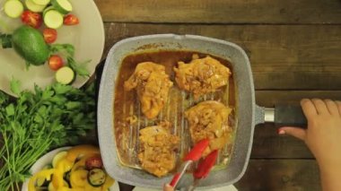 WOMANS el maşa ile bir ızgara Pan tavuk parçaları döner