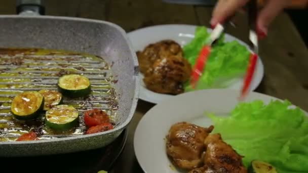 La mano femenina pone trozos de pollo y verduras en un plato con ensalada verde — Vídeos de Stock