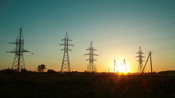 Pôr do sol no campo ao lado da estrada e passando carros em meio a linhas de alta tensão. Desfasamentos temporais . — Vídeo de Stock