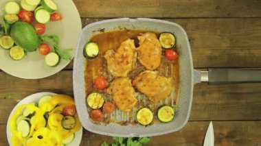 Dişi el ızgara tavada tavuk parçaları sebze koyar