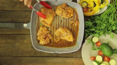 Bir ızgara tavada maşa tavuk ile karıştırma kadın el. Zaman turunda