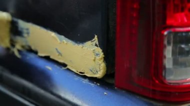 Bir adam araba vücudun pas içermeyen alanda metal macun koyar