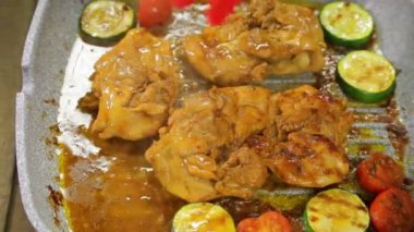 Kadın el ızgara tava üzerinde maşa ve tavuk ile sebze parçaları döner.