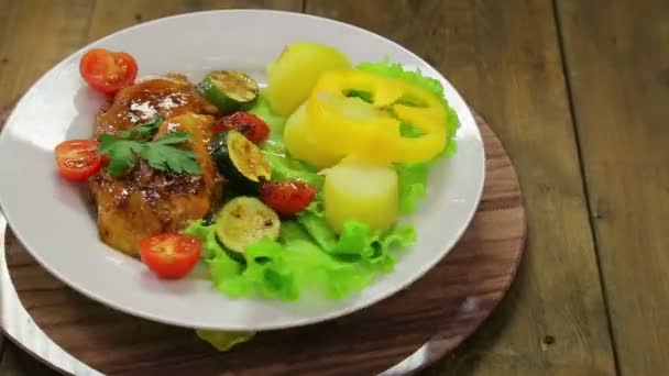 Un plato giratorio con un plato de pollo a la parrilla y un guarnición de verduras — Vídeo de stock