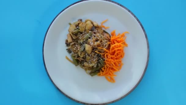 Il piatto tailandese di tagliatelle di riso con pollo e verdure e sesamo con carote coreane ruota in un cerchio . — Video Stock