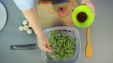Dişi el bir tavada soğan ve fasulye karıştırır ve champignon mantar keser