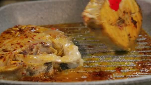 Female hand turns grilled fish steaks with tongs — Stock Video