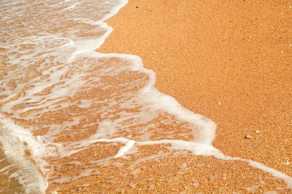 The sandy shore on which the sea wave runs over with foam. — Stock Photo, Image