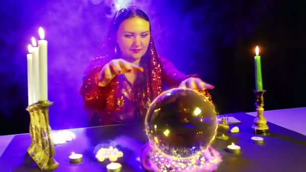 Eine Zigeunerin im Zaubersalon zaubert mit einer Kristallkugel, aus der das Feuerzeichen Schweizer Franken erscheint — Stockvideo