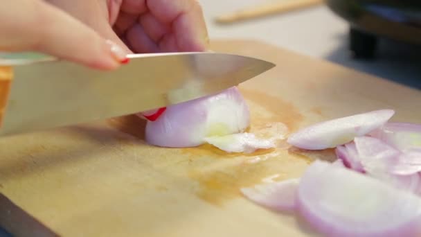 Frau schneidet rote Zwiebeln auf einem Holzbrett. — Stockvideo