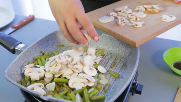 Vrouw voegt gesneden champignons aan de pan met groene bonen. — Stockvideo