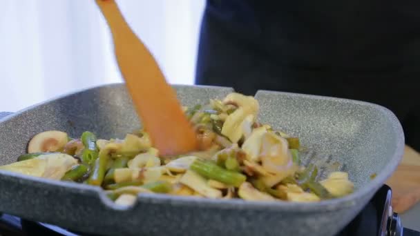 Une femme mélange des haricots verts avec des champignons avec un bâton de bois — Video