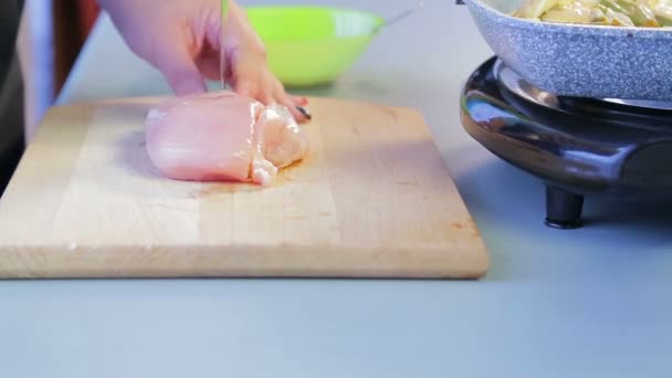 Mujer rebanadas filete de pollo con un cuchillo en una tabla de madera. Vueltas de tiempo — Vídeos de Stock